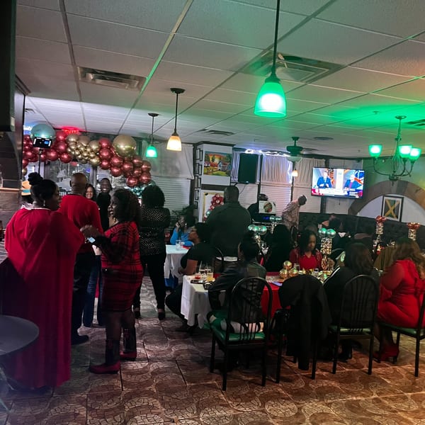 Guests socializing and dining at Trelawny Fusion Kitchen, with festive balloons and green lighting.