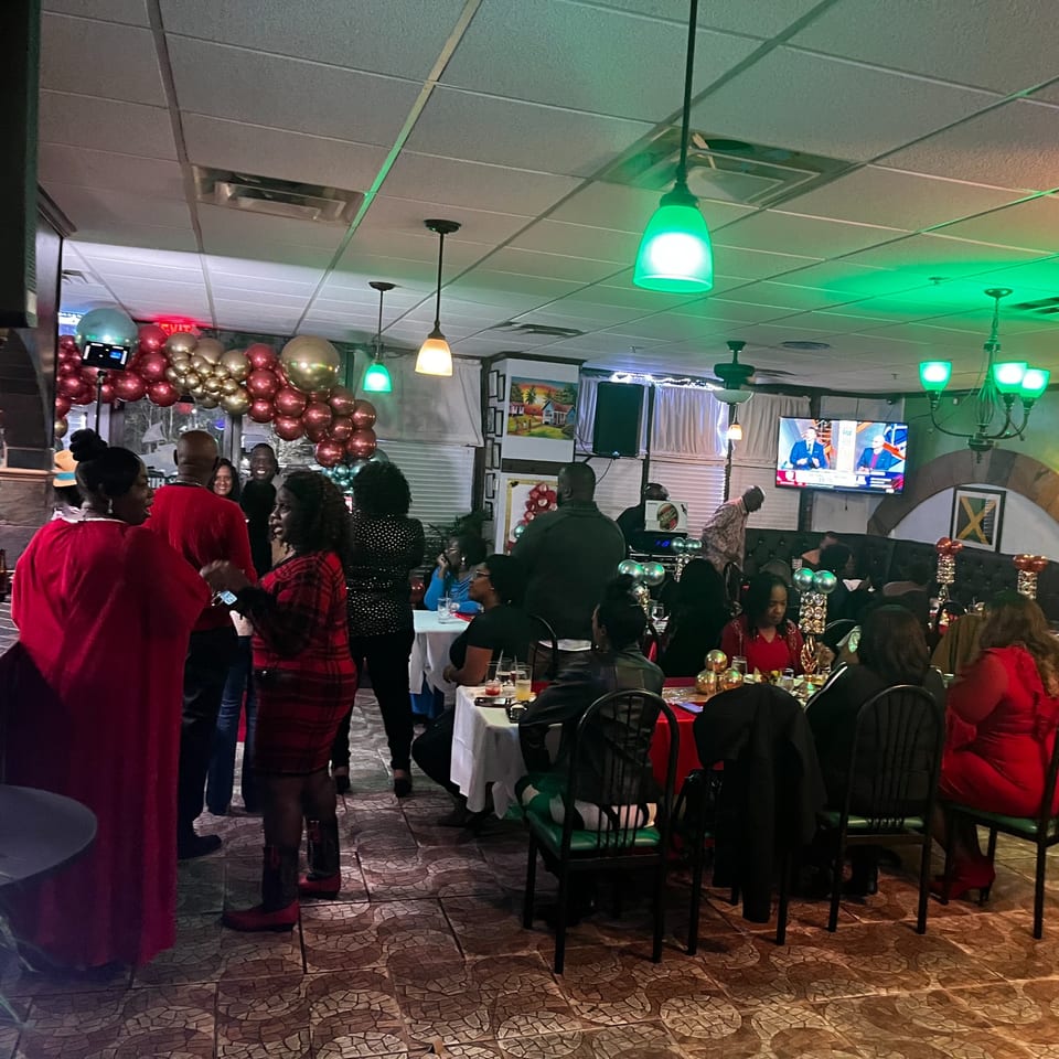 Guests socializing and dining at Trelawny Fusion Kitchen, with festive balloons and green lighting.