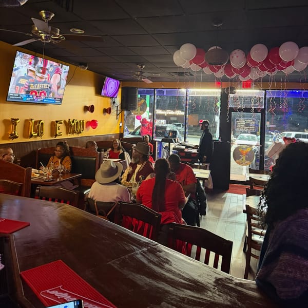 Patrons enjoying the lively atmosphere at Trelawny Fusion Kitchen, with balloons and a DJ setup.