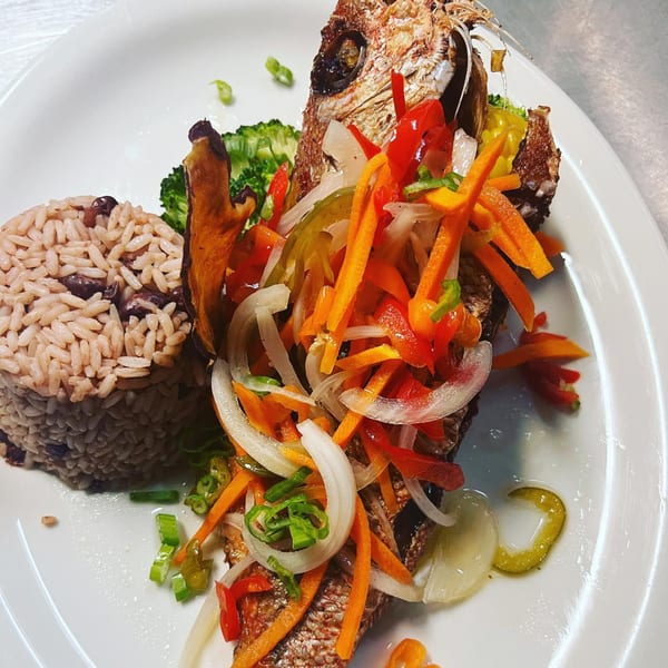 Trelawny Fusion Kitchen's Jamaican fried fish, topped with colorful escovitch vegetables, served with rice and peas.